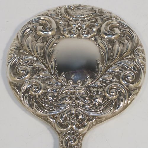 A very pretty Sterling Silver hand-mirror, having a round body with hand-chased floral and scroll decoration surrounding a central vacant cartouche, and a round bevelled mirror with rope-twist border. This beautiful silver hand mirror was made in Birmingham in 1982. The dimensions of this fine hand-made silver hand mirror are length 23.5 cms (9.25 inches), and diameter of main body 12.5 cms (5 inches).