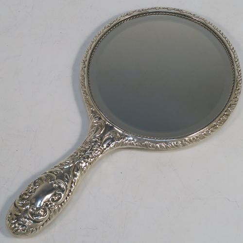 A very pretty Sterling Silver hand-mirror, having a round body with hand-chased floral border surrounding a group of winged cherub faces, and a round bevelled mirror with rope-twist border. This beautiful silver hand mirror was made in Birmingham in 1981. The dimensions of this fine hand-made silver hand mirror are length 23.5 cms (9.25 inches), and diameter of main body 12.5 cms (5 inches).