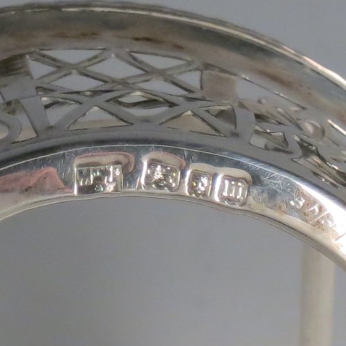 An Antique Edwardian Sterling Silver preserve, jam and honey pot holder, having a blue and frosted glass pot, sitting in a hand-pierced frame with floral and geometric decoration, with applied gadroon borders, a reeded and pierced loop handle, and all sitting on four cast floral feet. Made by Mappin and Webb of London in 1907. The dimensions of this fine hand-made antique silver and glass preserve holder are length 21 cms (8.25 inches), width 11 cms (4.25 inches), height 17.5 cms (7 inches), and it weighs approx. 243g (7.8 troy ounces).