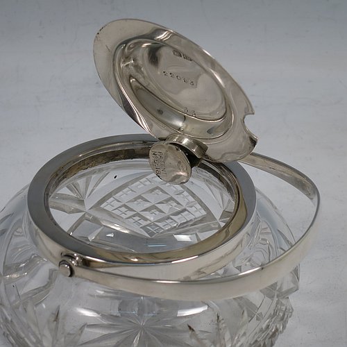 A Sterling Silver and crystal honey or jam jar, having a round bellied body with hand-cut geometrical design and a star-cut base, a plain round mount, with a mechanical swing-handled hinged and domed lid. Made by Hukin & Heath of Birminghamn in 1928. The dimensions of this fine hand-made silver and glass conserve jar are height (inc. handle) 12.5 cms (5 inches), and diameter 11 cms (4.3 inches).