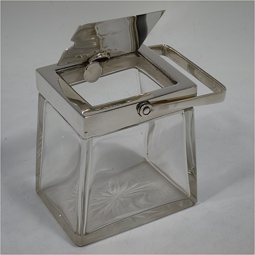 A very handsome Arts and Crafts style Antique Edwardian Sterling Silver and crystal honey, jam, or conserve jar, having a plain rectangular body with tapering sides and star-cut base, a plain rectangular mount, with a mechanical swing-handled hinged lid and a slot for a conserve spoon. Made by Heath and Middleton of Birmingham in 1906. The dimensions of this fine hand-made Arts and Crafts silver and crystal conserve, jam, or honey jar are height (inc. handle) 14.5 cms (5.25 inches), width 9 cms (3.5 inches), and depth 6.5 cms (2.5 inches).