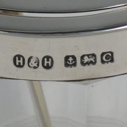 A very handsome Art Deco style Sterling Silver and crystal honey or jam jar, having a plain cylindrically panelled body with hand-cut reeded bands and a star-cut base, a plain round mount with a mechanical swing-handled hinged lid, and an original spoon. Made by Hukin and Heath of Birmingham in 1927. The dimensions of this fine hand-made silver and crystal jam or honey jar are height (inc. handle) 15 cms (6 inches), and diameter 8.5 cms (3.25 inches).