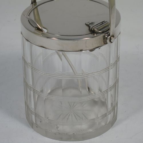 A very handsome Art Deco style Sterling Silver and crystal honey or jam jar, having a plain cylindrically panelled body with hand-cut reeded bands and a star-cut base, a plain round mount with a mechanical swing-handled hinged lid, and an original spoon. Made by Hukin and Heath of Birmingham in 1927. The dimensions of this fine hand-made silver and crystal jam or honey jar are height (inc. handle) 15 cms (6 inches), and diameter 8.5 cms (3.25 inches).
