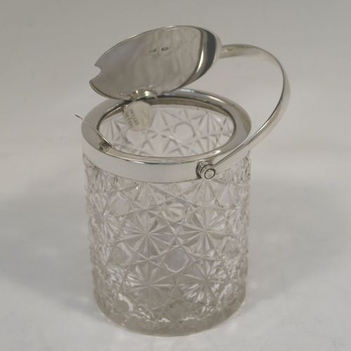 A very handsome Antique Victorian Sterling Silver and crystal honey or jam jar, having a hobnail and star-cut cylindrical crystal body with a star-cut base, a plain round mount with a mechanical swing-handled hinged lid, and an original spoon. This beautiful antique silver jam or honey jar was made by Heath and Middleton of London in 1901. The dimensions of this fine hand-made antique silver and crystal jam or honey jar are height (inc. handle) 14 cms (5.5 inches), and diameter 8 cms (3 inches). Please note that this item is crested.
