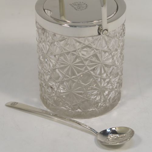 A very handsome Antique Victorian Sterling Silver and crystal honey or jam jar, having a hobnail and star-cut cylindrical crystal body with a star-cut base, a plain round mount with a mechanical swing-handled hinged lid, and an original spoon. This beautiful antique silver jam or honey jar was made by Heath and Middleton of London in 1901. The dimensions of this fine hand-made antique silver and crystal jam or honey jar are height (inc. handle) 14 cms (5.5 inches), and diameter 8 cms (3 inches). Please note that this item is crested.