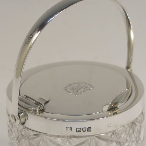 A very handsome Antique Victorian Sterling Silver and crystal honey or jam jar, having a hobnail and star-cut cylindrical crystal body with a star-cut base, a plain round mount with a mechanical swing-handled hinged lid, and an original spoon. This beautiful antique silver jam or honey jar was made by Heath and Middleton of London in 1901. The dimensions of this fine hand-made antique silver and crystal jam or honey jar are height (inc. handle) 14 cms (5.5 inches), and diameter 8 cms (3 inches). Please note that this item is crested.