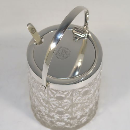 A very handsome Antique Victorian Sterling Silver and crystal honey or jam jar, having a hobnail and star-cut cylindrical crystal body with a star-cut base, a plain round mount with a mechanical swing-handled hinged lid, and an original spoon. This beautiful antique silver jam or honey jar was made by Heath and Middleton of London in 1901. The dimensions of this fine hand-made antique silver and crystal jam or honey jar are height (inc. handle) 14 cms (5.5 inches), and diameter 8 cms (3 inches). Please note that this item is crested.