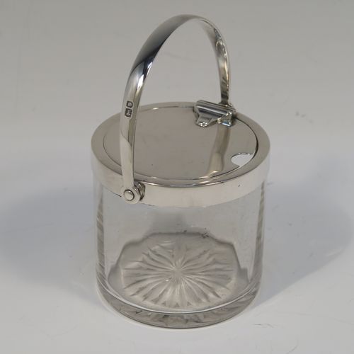 A very elegant Antique Edwardian Sterling Silver and crystal honey or jam jar, having a plain cylindrical and panelled body with star-cut base, a plain round mount, and a plain mechanical swing-handled hinged lid. This handsome silver honey or jam jar was made by Heath and Middleton of London in 1903. The dimensions of this fine hand-made antique silver and crystal conserve jar are height (inc. handle) 11 cms (4.25 inches), and diameter 7 cms (2.75 inches).   
