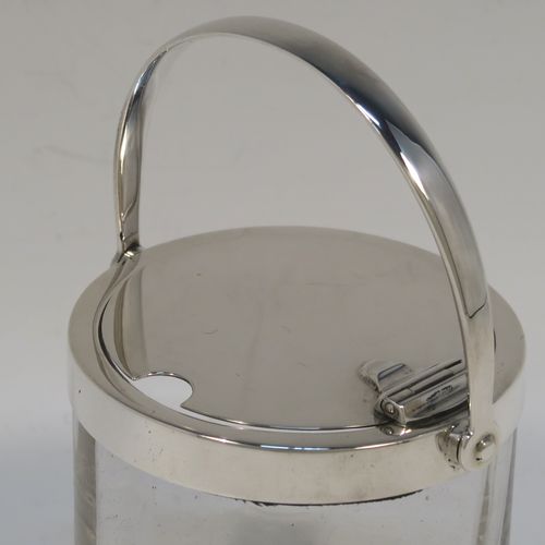 A very elegant Antique Edwardian Sterling Silver and crystal honey or jam jar, having a plain cylindrical and panelled body with star-cut base, a plain round mount, and a plain mechanical swing-handled hinged lid. This handsome silver honey or jam jar was made by Heath and Middleton of London in 1903. The dimensions of this fine hand-made antique silver and crystal conserve jar are height (inc. handle) 11 cms (4.25 inches), and diameter 7 cms (2.75 inches).