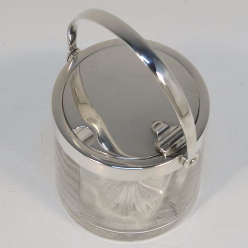 A very elegant Antique Edwardian Sterling Silver and crystal honey or jam jar, having a plain cylindrical and panelled body with star-cut base, a plain round mount, and a plain mechanical swing-handled hinged lid. This handsome silver honey or jam jar was made by Heath and Middleton of London in 1903. The dimensions of this fine hand-made antique silver and crystal conserve jar are height (inc. handle) 11 cms (4.25 inches), and diameter 7 cms (2.75 inches).