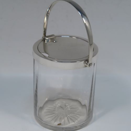 A very elegant Art Deco Sterling Silver and crystal honey or jam jar, having a plain cylindrical and panelled body with star-cut base, a plain round mount, and a plain mechanical swing-handled hinged lid with cut-out for a honey or jam spoon (not included). This handsome silver honey or jam jar was made by Asprey of Birmingham in 1935. The dimensions of this fine hand-made silver and crystal conserve jar are height (inc. handle) 15 cms (6 inches), and diameter 8 cms (3 inches).