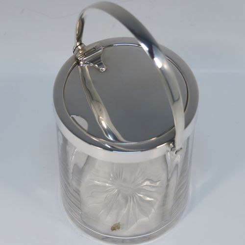 A very elegant Art Deco Sterling Silver and crystal honey or jam jar, having a plain cylindrical and panelled body with star-cut base, a plain round mount, and a plain mechanical swing-handled hinged lid with cut-out for a honey or jam spoon (not included). This handsome silver honey or jam jar was made by Asprey of Birmingham in 1935. The dimensions of this fine hand-made silver and crystal conserve jar are height (inc. handle) 15 cms (6 inches), and diameter 8 cms (3 inches).