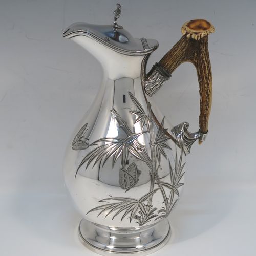 A beautiful and unusual Aesthetic style Antique Victorian Silver-Plated hot water or milk pot, having a round bellied body, with hand-chased butterfly and floral decoration, a horn antler handle, a hinged lid with a finial, and all sitting on a round pedestal foot. This beautiful antique Aesthetic silver plated hot milk or water pot was made by James Dixon and Sons of Sheffield in ca. 1880. The dimensions of this fine hand-made antique silver-plated serving pot are height 22 cms (8.75 inches), and length 14 cms (5.5 inches).   