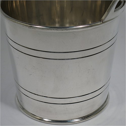 An Antique Edwardian silver plated ice bucket, having a plain round body with tapering straight sides and hand-chased reeded decoration, an internal removable dry ice drainer, with two top cast side handles, and all sitting on a flat base. Made by Collins of London in ca. 1910. The dimensions of this fine hand-made antique silver-plated ice bucket are height 15.5 cms (6 inches), and diameter at lip 14 cms (5.5 inches).   