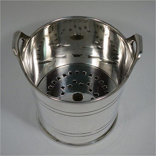 An Antique Edwardian silver plated ice bucket, having a plain round body with tapering straight sides and hand-chased reeded decoration, an internal removable dry ice drainer, with two top cast side handles, and all sitting on a flat base. Made by Collins of London in ca. 1910. The dimensions of this fine hand-made antique silver-plated ice bucket are height 15.5 cms (6 inches), and diameter at lip 14 cms (5.5 inches).   