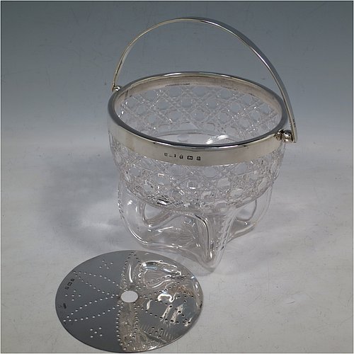 An Antique Victorian Sterling Silver and hand-cut crystal ice bucket, having a round hob-nail cut crystal body sitting on four unusual conjoined legs, with an internal removable dry ice drainer, a plain silver rim, and a hinged swing handle. Made by the Henry Williamson Ltd., of Birmingham in 1900. The dimensions of this fine hand-made antique silver and crystal ice bucket are height (excluding handle) 12.5 cms (5 inches), and diameter at lip 12.5 cms (5 inches).