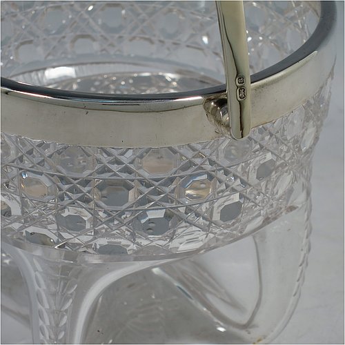 An Antique Victorian Sterling Silver and hand-cut crystal ice bucket, having a round hob-nail cut crystal body sitting on four unusual conjoined legs, with an internal removable dry ice drainer, a plain silver rim, and a hinged swing handle. Made by the Henry Williamson Ltd., of Birmingham in 1900. The dimensions of this fine hand-made antique silver and crystal ice bucket are height (excluding handle) 12.5 cms (5 inches), and diameter at lip 12.5 cms (5 inches).