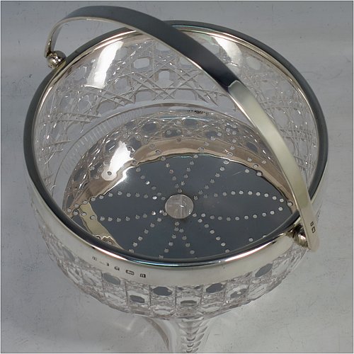 An Antique Victorian Sterling Silver and hand-cut crystal ice bucket, having a round hob-nail cut crystal body sitting on four unusual conjoined legs, with an internal removable dry ice drainer, a plain silver rim, and a hinged swing handle. Made by the Henry Williamson Ltd., of Birmingham in 1900. The dimensions of this fine hand-made antique silver and crystal ice bucket are height (excluding handle) 12.5 cms (5 inches), and diameter at lip 12.5 cms (5 inches).