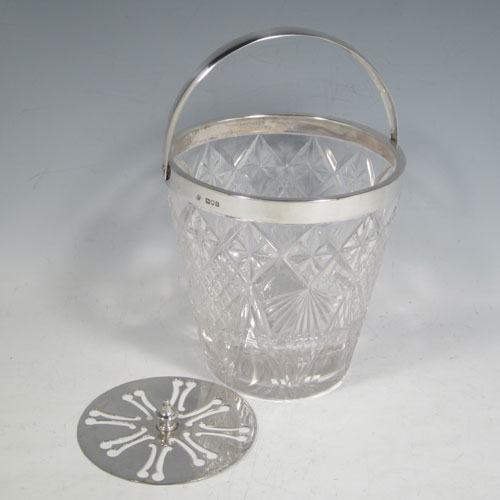 Antique Victorian sterling silver ice bucket, having a round hand-cut crystal body with tapering sides, an internal removable dry ice drainer, a plain silver rim, and a hinged swing handle. Made by the Dixon Brothers of London in 1899. The dimensions of this fine hand-made silver ice bucket are height (excluding handle) 13 cms (5 inches), and diameter at lip 13 cms (5 inches). Please note that there is a small crack in the top border that is hidden by the silver rim.
