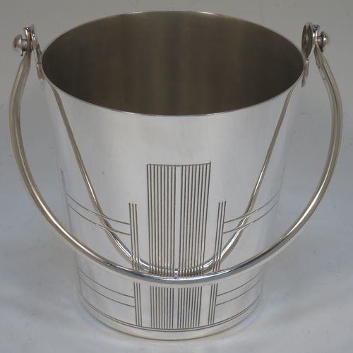 A very stylish Art Deco Silver Plated ice bucket, having a plain round body with tapering straight sides and hand-chased reeded decoration, an internal removable dry ice drainer, with a hinged loop handle, and all sitting on a flat base. Made in ca. 1930. The dimensions of this fine hand-made silver-plated ice bucket are height (not including handle) 11 cms (4.3 inches), and diameter at lip 11 cms (4.3 inches).