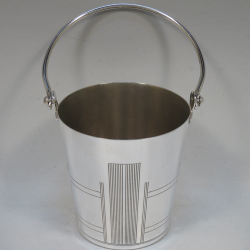 A very stylish Art Deco Silver Plated ice bucket, having a plain round body with tapering straight sides and hand-chased reeded decoration, an internal removable dry ice drainer, with a hinged loop handle, and all sitting on a flat base. Made in ca. 1930. The dimensions of this fine hand-made silver-plated ice bucket are height (not including handle) 11 cms (4.3 inches), and diameter at lip 11 cms (4.3 inches).