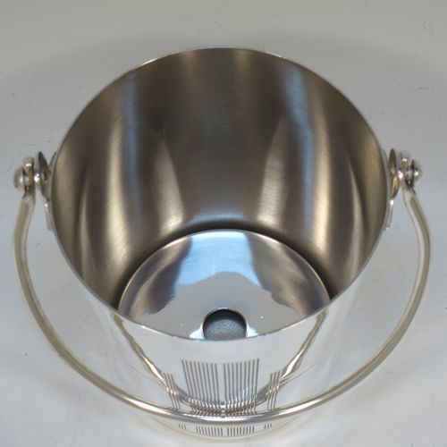 A very stylish Art Deco Silver Plated ice bucket, having a plain round body with tapering straight sides and hand-chased reeded decoration, an internal removable dry ice drainer, with a hinged loop handle, and all sitting on a flat base. Made in ca. 1930. The dimensions of this fine hand-made silver-plated ice bucket are height (not including handle) 11 cms (4.3 inches), and diameter at lip 11 cms (4.3 inches).