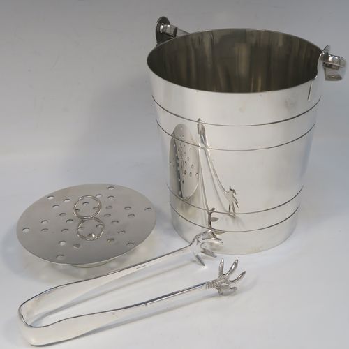 A very stylish Art Deco Silver Plated ice bucket, having a plain round body with tapering straight sides and hand-chased reeded decoration, an internal removable dry ice drainer, a pair of ice tongs, and with a hinged loop handle, and all sitting on a flat base. This elegant silver-plated ice bucket was made in ca. 1930. The dimensions of this fine hand-made silver-plated ice bucket are height (not including handle) 16 cms (6.3 inches), and diameter at lip 14.5 cms (5.75 inches).   