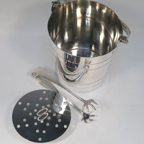 A very stylish Art Deco Silver Plated ice bucket, having a plain round body with tapering straight sides and hand-chased reeded decoration, an internal removable dry ice drainer, a pair of ice tongs, and with a hinged loop handle, and all sitting on a flat base. This elegant silver-plated ice bucket was made in ca. 1930. The dimensions of this fine hand-made silver-plated ice bucket are height (not including handle) 16 cms (6.3 inches), and diameter at lip 14.5 cms (5.75 inches).   
