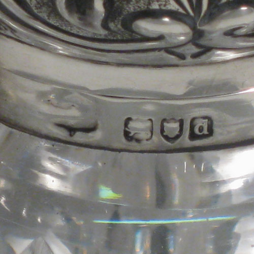 Antique Victorian Art Nouveau sterling silver inkstand, having a hand-chased hinged lid with floral decoration, a glass insert for a smaller amount of ink, and a heavy hand-cut round crystal body that can hold a large amount of ink, with a star cut base. Made by Mappin and Webb of London in 1899. Height 12.5 cms (5 inches), diameter 10 cms (4 inches).
