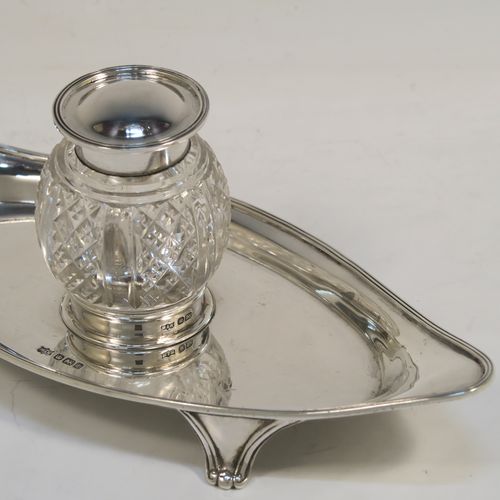 An elegant Antique Sterling Silver single bottle inkstand, with a plain oval boat-shaped body, having an applied reeded border, a single removable cut-crystal ink bottle with hinged lid, and all sitting on four cast flanged feet. This pretty antique silver inkstand was made by Mappin and Webb of Sheffield in 1911. The dimensions of this fine hand-made antique sterling silver inkstand are length 21 cms (8.25 inches), width 9.5 cms (3.75 inches), and it weighs approx. 150g (4.8 troy ounces).