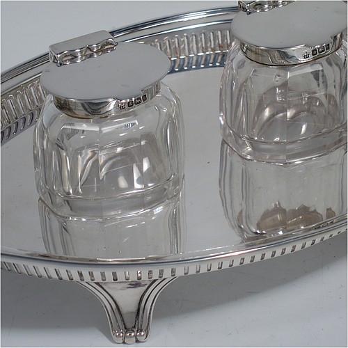 An Antique Edwardian Sterling Silver two bottle double inkstand, with an oval boat-shaped body, having a hand-pierced gallery border and hand-engraved ends with neoclassical style engraving, two removable cut-crystal ink bottles with hinged lids, and all sitting on four cast flanged feet. Made by Hawksworth and Eyre of Sheffield in 1902. The dimensions of this fine hand-made antique sterling silver double inkstand are length 28 cms (11 inches), width 14 cms (5.5 inches), and it weighs approx. 350g (11.2 troy ounces).  