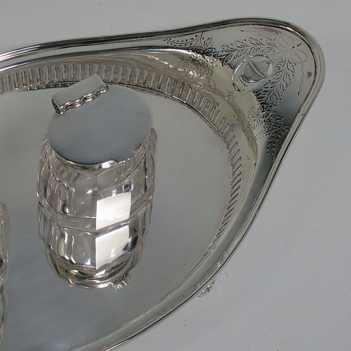 An Antique Edwardian Sterling Silver two bottle double inkstand, with an oval boat-shaped body, having a hand-pierced gallery border and hand-engraved ends with neoclassical style engraving, two removable cut-crystal ink bottles with hinged lids, and all sitting on four cast flanged feet. Made by Hawksworth and Eyre of Sheffield in 1902. The dimensions of this fine hand-made antique sterling silver double inkstand are length 28 cms (11 inches), width 14 cms (5.5 inches), and it weighs approx. 350g (11.2 troy ounces).  