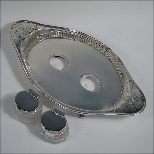 An Antique Edwardian Sterling Silver two bottle double inkstand, with an oval boat-shaped body, having a hand-pierced gallery border and hand-engraved ends with neoclassical style engraving, two removable cut-crystal ink bottles with hinged lids, and all sitting on four cast flanged feet. Made by Hawksworth and Eyre of Sheffield in 1902. The dimensions of this fine hand-made antique sterling silver double inkstand are length 28 cms (11 inches), width 14 cms (5.5 inches), and it weighs approx. 350g (11.2 troy ounces).  