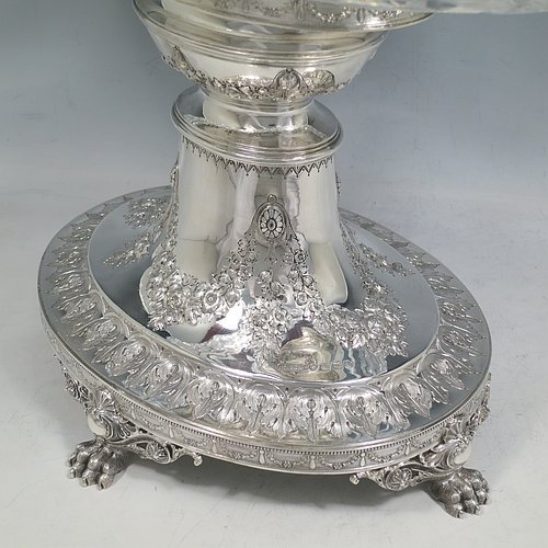 An Antique Victorian Sterling Silver jardinière / epergne, having an oval body with hand-cut crystal bowl, sitting on a cast and hand-chased stand with neoclassical style floral work, all standing on four cast lions-paw feet. Made by Henry Wilkinson of Birmingham in 1882. The dimensions of this fine hand-made antique silver and crystal jardinière / epergne are length 34 cms (13.5 inches), width 25 cms (10 inches), height 30.5 cms (12 inches), and it weighs approx. 1,118g (36 troy ounces).