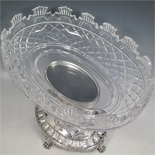 An Antique Victorian Sterling Silver jardinière / epergne, having an oval body with hand-cut crystal bowl, sitting on a cast and hand-chased stand with neoclassical style floral work, all standing on four cast lions-paw feet. Made by Henry Wilkinson of Birmingham in 1882. The dimensions of this fine hand-made antique silver and crystal jardinière / epergne are length 34 cms (13.5 inches), width 25 cms (10 inches), height 30.5 cms (12 inches), and it weighs approx. 1,118g (36 troy ounces).