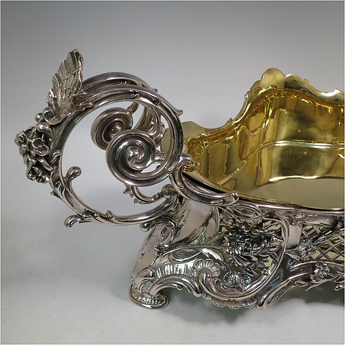 A very impressive and pretty Antique Victorian silver jardiniere, having an oval hand-chased and pierced body with applied floral decoration, two cast scroll-work handles with shell thumb-pieces, sitting on four cast foliate feet, and with an original gold-gilt interior liner. Probably German in origin and made in circa. 1880 in the 800 standard silver. The dimensions of this fine hand-made silver jardinière are Length 67 cms (26.5 inches), width 33 cms (13 inches), height 28 cms (11 inches), and it weighs approx. 4,140g (134 troy ounces).