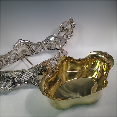 A very impressive and pretty Antique Victorian silver jardiniere, having an oval hand-chased and pierced body with applied floral decoration, two cast scroll-work handles with shell thumb-pieces, sitting on four cast foliate feet, and with an original gold-gilt interior liner. Probably German in origin and made in circa. 1880 in the 800 standard silver. The dimensions of this fine hand-made silver jardinière are Length 67 cms (26.5 inches), width 33 cms (13 inches), height 28 cms (11 inches), and it weighs approx. 4,140g (134 troy ounces).