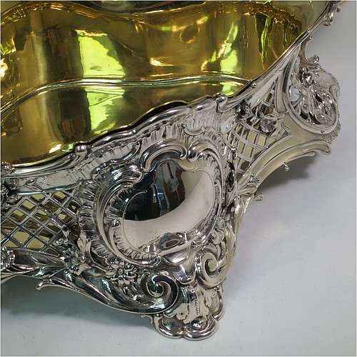 A very impressive and pretty Antique Victorian silver jardiniere, having an oval hand-chased and pierced body with applied floral decoration, two cast scroll-work handles with shell thumb-pieces, sitting on four cast foliate feet, and with an original gold-gilt interior liner. Probably German in origin and made in circa. 1880 in the 800 standard silver. The dimensions of this fine hand-made silver jardinière are Length 67 cms (26.5 inches), width 33 cms (13 inches), height 28 cms (11 inches), and it weighs approx. 4,140g (134 troy ounces).