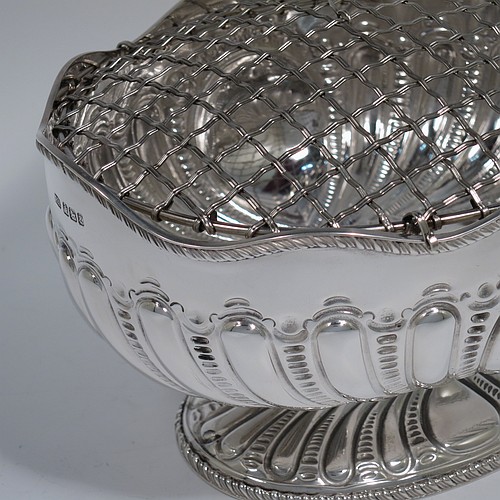 An Antique Victorian Sterling Silver flower Jardiniere, having an oval body, with an applied shaped gadroon border and hand-chased fluted decoration, with vacant round cartouches either side, and sitting on a matching pedestal foot. Made by Henry Atkins of Sheffield in 1892. The dimensions of this fine hand-made antique silver Jardiniere for flowers are length 20 cms (8 inches), width 15 cms (6 inches), height 11 cms (4.25 inches), and it weighs approx. 373g (12 troy ounces). Please note that this piece has its own hand-made to fit silver-plated rose grill.