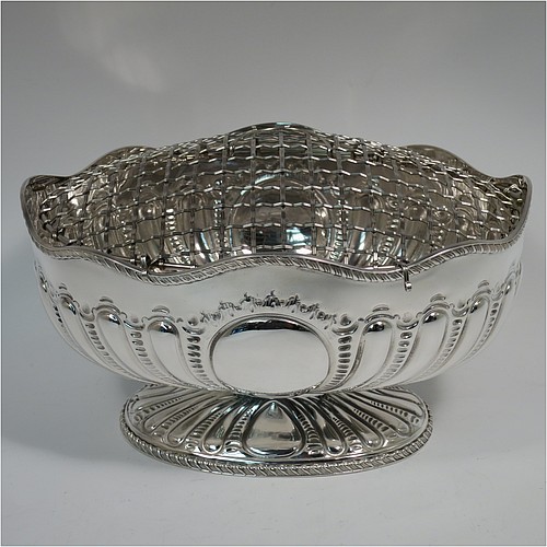 An Antique Victorian Sterling Silver flower Jardiniere, having an oval body, with an applied shaped gadroon border and hand-chased fluted decoration, with vacant round cartouches either side, and sitting on a matching pedestal foot. Made by Henry Atkins of Sheffield in 1892. The dimensions of this fine hand-made antique silver Jardiniere for flowers are length 20 cms (8 inches), width 15 cms (6 inches), height 11 cms (4.25 inches), and it weighs approx. 373g (12 troy ounces). Please note that this piece has its own hand-made to fit silver-plated rose grill.