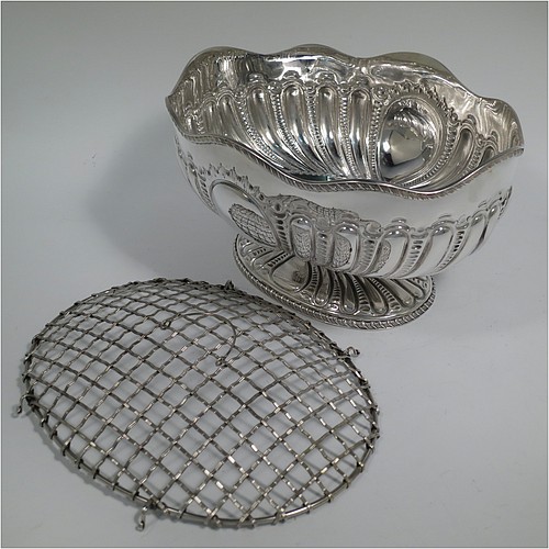An Antique Victorian Sterling Silver flower Jardiniere, having an oval body, with an applied shaped gadroon border and hand-chased fluted decoration, with vacant round cartouches either side, and sitting on a matching pedestal foot. Made by Henry Atkins of Sheffield in 1892. The dimensions of this fine hand-made antique silver Jardiniere for flowers are length 20 cms (8 inches), width 15 cms (6 inches), height 11 cms (4.25 inches), and it weighs approx. 373g (12 troy ounces). Please note that this piece has its own hand-made to fit silver-plated rose grill.
