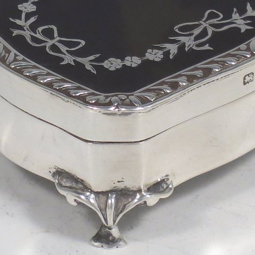 A very pretty Antique Edwardian Sterling Silver and tortoise-shell jewellery box, having a shaped rectangular body, a tortoise-shell hinged lid with in-laid flowers and ribbon bows, an applied gadroon border, a dark blue velvet-lined interior, and sitting on four cast foliate legs. Made by Henry Miller of Birmingham in 1910. The dimensions of this fine hand-made antique silver and tortoise-shell jewelery box are length 7 cms (2.75 inches), width 5.5 cms (2.25 inches), and height 3 cms (1.25 inches).