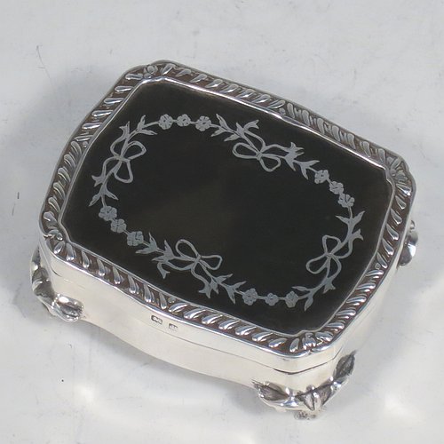 A very pretty Antique Edwardian Sterling Silver and tortoise-shell jewellery box, having a shaped rectangular body, a tortoise-shell hinged lid with in-laid flowers and ribbon bows, an applied gadroon border, a dark blue velvet-lined interior, and sitting on four cast foliate legs. Made by Henry Miller of Birmingham in 1910. The dimensions of this fine hand-made antique silver and tortoise-shell jewelery box are length 7 cms (2.75 inches), width 5.5 cms (2.25 inches), and height 3 cms (1.25 inches).