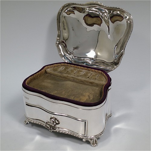 An Antique Edwardian Sterling Silver large jewellery box, having a rectangular shaped casket style body with rounded corners and applied pearl and bead borders, a plain domed hinged lid covering a velvet-lined interior, a pull-out drawer with a cast swing handle, and all sitting on four cast foliate feet. Made by Nathan and Hayes of Chester in 1907. The dimensions of this fine hand-made antique silver jewellery box are length 13.5 cms (5.3 inches), width 11 cms (4.3 inches), and height 11 cms (4.3 inches).