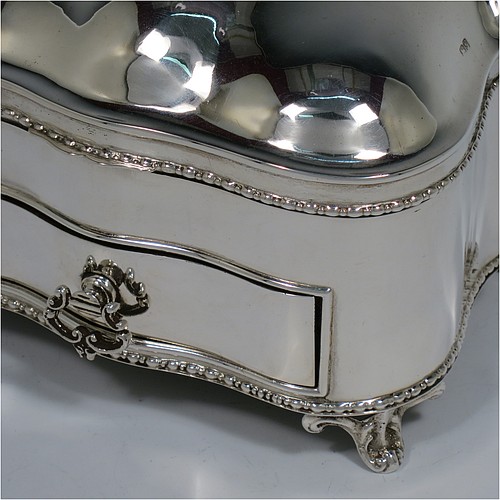 An Antique Edwardian Sterling Silver large jewellery box, having a rectangular shaped casket style body with rounded corners and applied pearl and bead borders, a plain domed hinged lid covering a velvet-lined interior, a pull-out drawer with a cast swing handle, and all sitting on four cast foliate feet. Made by Nathan and Hayes of Chester in 1907. The dimensions of this fine hand-made antique silver jewellery box are length 13.5 cms (5.3 inches), width 11 cms (4.3 inches), and height 11 cms (4.3 inches).