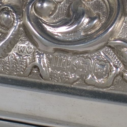 A very pretty Antique Edwardian Sterling Silver large jewellery box, having a rectangular shaped casket style body, with hand-chased floral and scroll decoration, a lockable hinged lid with a vacant central cartouche, a light blue satin-lined interior, all sitting on a flat base. Made by William Comyns of London in 1907. The dimensions of this fine hand-made silver jewellery box are length 27 cms (10.5 inches), width 13 cms (5 inches), and height 9 cms (3.5 inches).