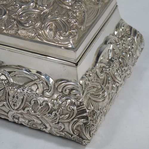 A very pretty Antique Edwardian Sterling Silver large jewellery box, having a rectangular shaped casket style body, with hand-chased floral and scroll decoration, a lockable hinged lid with a vacant central cartouche, a light blue satin-lined interior, all sitting on a flat base. Made by William Comyns of London in 1907. The dimensions of this fine hand-made silver jewellery box are length 27 cms (10.5 inches), width 13 cms (5 inches), and height 9 cms (3.5 inches).