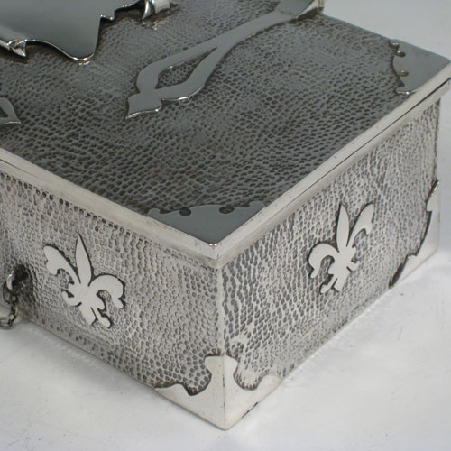 Antique Edwardian sterling silver Arts and Crafts style casket jewelery box, having a hand-hammered rectangular body, with cut-card work in a Medieval style, a hinged lock and chain, and a velvet lined interior. Made by J. Gilbert of Birmingham in 1906. Height 6.5 cms (2.5 inches), length 18.5 cms (7.25 inches), depth 10 cms (4 inches). Weight approx. 400g (13 troy ounces).