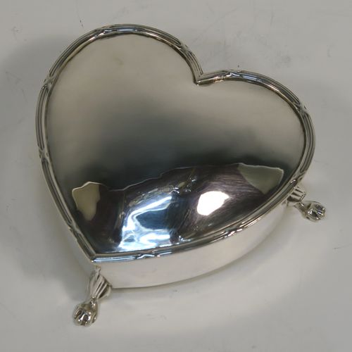 A pretty Antique Edwardian Sterling Silver jewellery box, having a plain heart-shaped body with straight sides, a hinged lid with an applied ribbon and reed border, and dark-blue velvet-lined interior, and all sitting on three cast lions-paw feet. This beautiful heart-shaped silver jewelery box was made by T. H. Hazlewood of Birmingham in 1907. The dimensions of this fine hand-made antique silver jewelery box are length 10 cms (4 inches), width 11 cms (4.3 inches), and height 4 cms (1.5 inches).
