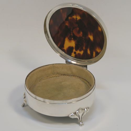 A very pretty Antique Sterling Silver and tortoise-shell jewellery box, having a plain round body, an in-laid tortoise-shell hinged lid, a cream coloured velvet-lined base, and sitting on three cast foliate feet. This beautiful silver and tortoise shell jewellery box was made by Synyer and Beddoes of Birmingham in 1919. The dimensions of this fine hand-made antique silver jewelery box are diameter 9 cms (3.5 inches), and height 4.5 cms (1.75 inches).